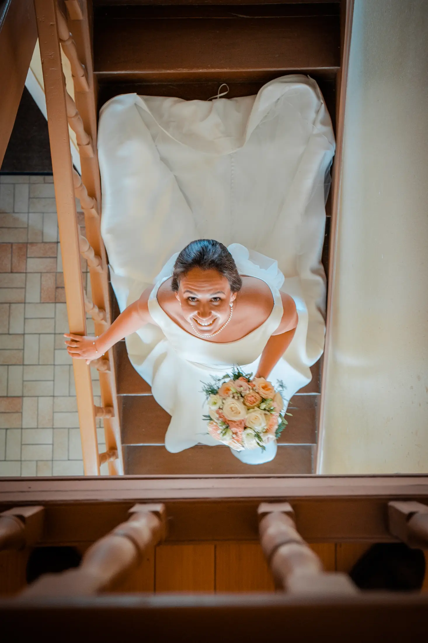 Une mariée sourit en regardant l’appareil depuis l’escalier